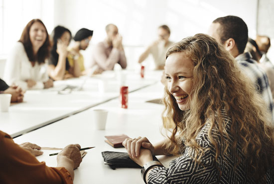 A college-age young woman laughing during a meeting at her internship