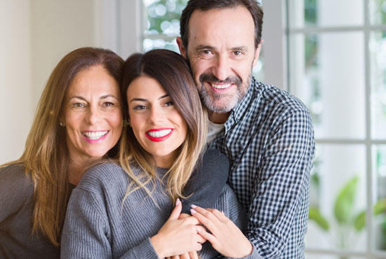 Parents hugging their college-age daughter